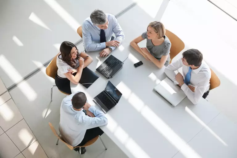 Team aus fünf Personen diskutiert an einem Meeting-Tisch