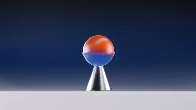 Halb orange, halb blaue Kugel balanciert auf einem silbernen Kegel