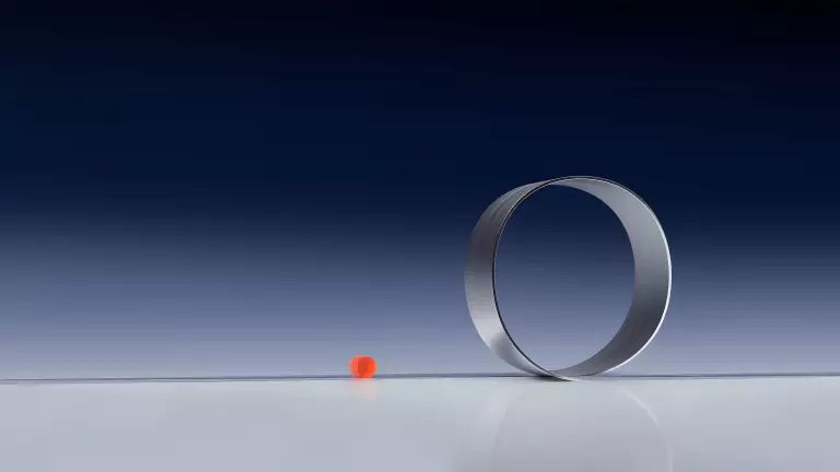 Aufrecht stehender Metallring neben einer kleinen orangefarbenen Kugel