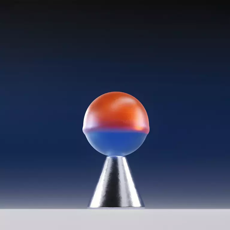 Halb orange, halb blaue Kugel balanciert auf einem silbernen Kegel