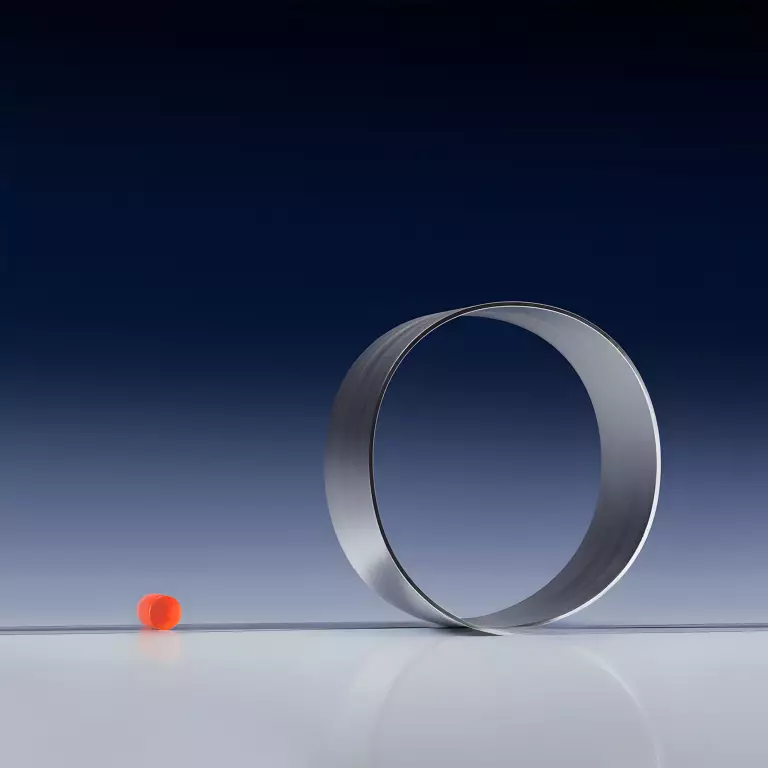 Aufrecht stehender Metallring neben einer kleinen orangefarbenen Kugel